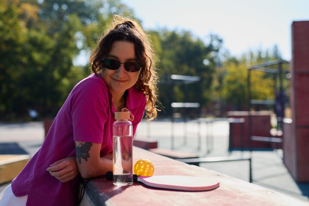 Cheerful pickleball player resting on a sports ground after the game